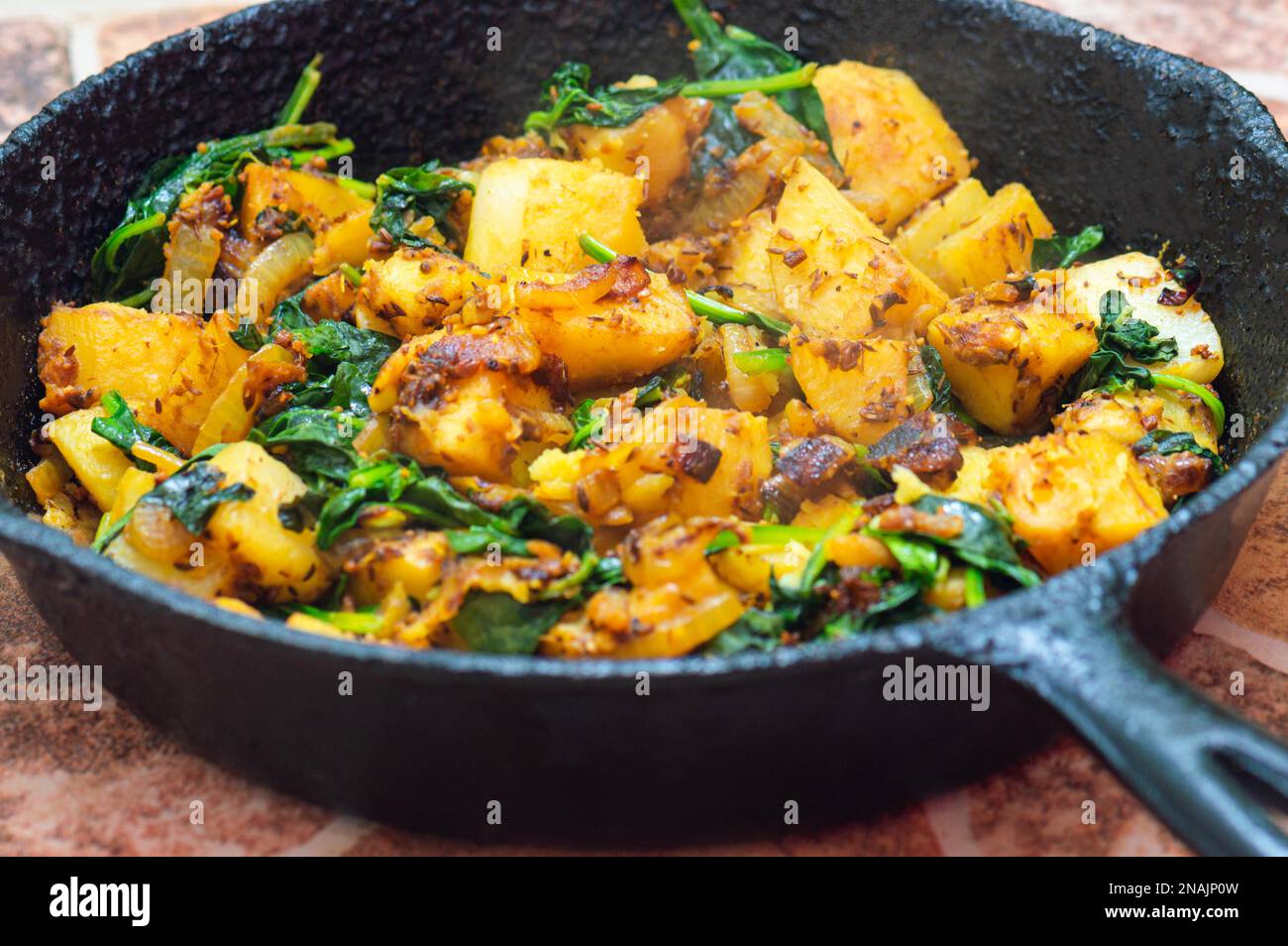 Saag Aloo, Indian style spinach and potato dish in cast iron pan Stock