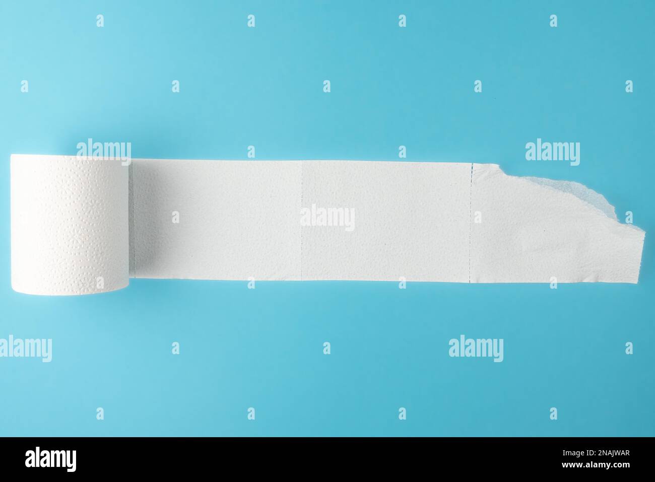 partially unrolled toilet paper roll isolated on blue background Stock Photo