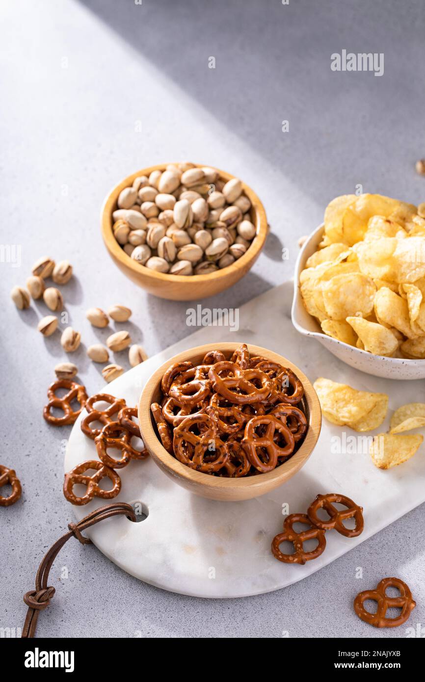 Variety of salty snacks on the table with pretzels, pistachios and