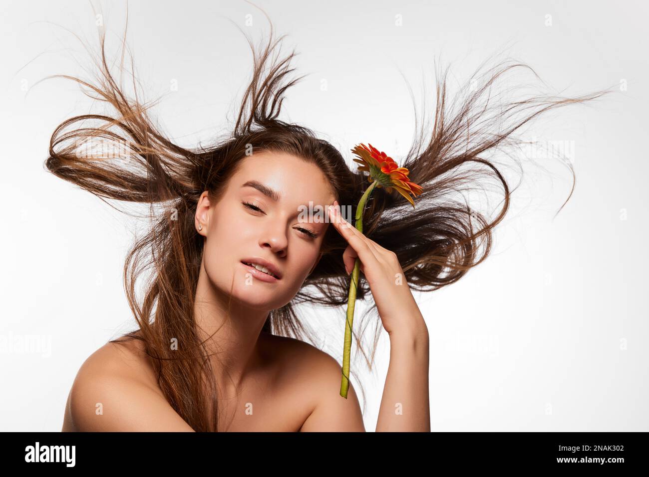 Beautiful young girl with wellkept clean skin posing with gerbera