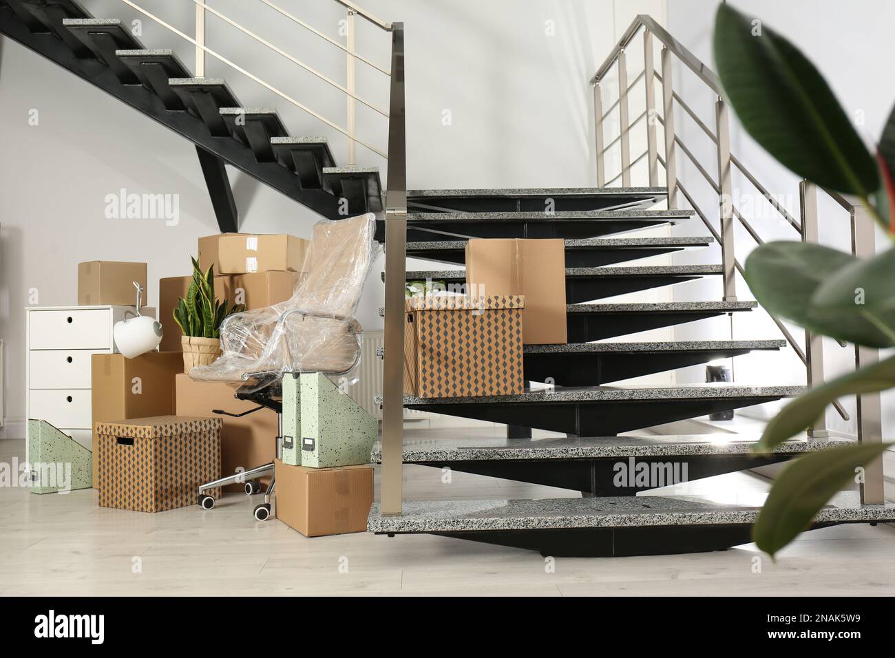 Cardboard boxes and packed chair near stairs in office. Moving day