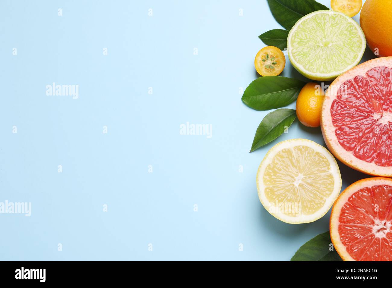 Fresh juicy citrus fruits with green leaves on light blue background ...