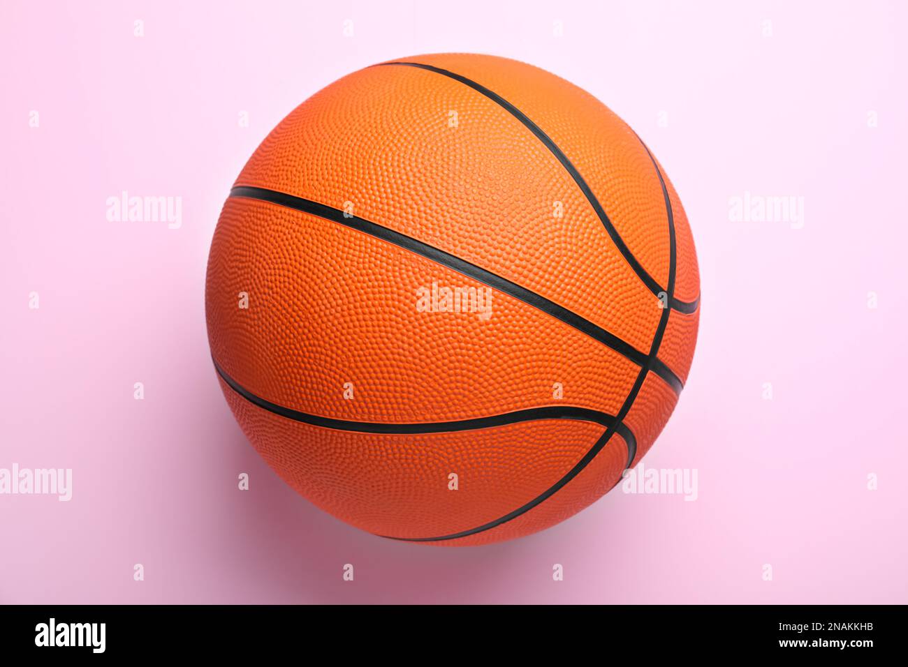 Orange ball on pink background, top view. Basketball equipment Stock