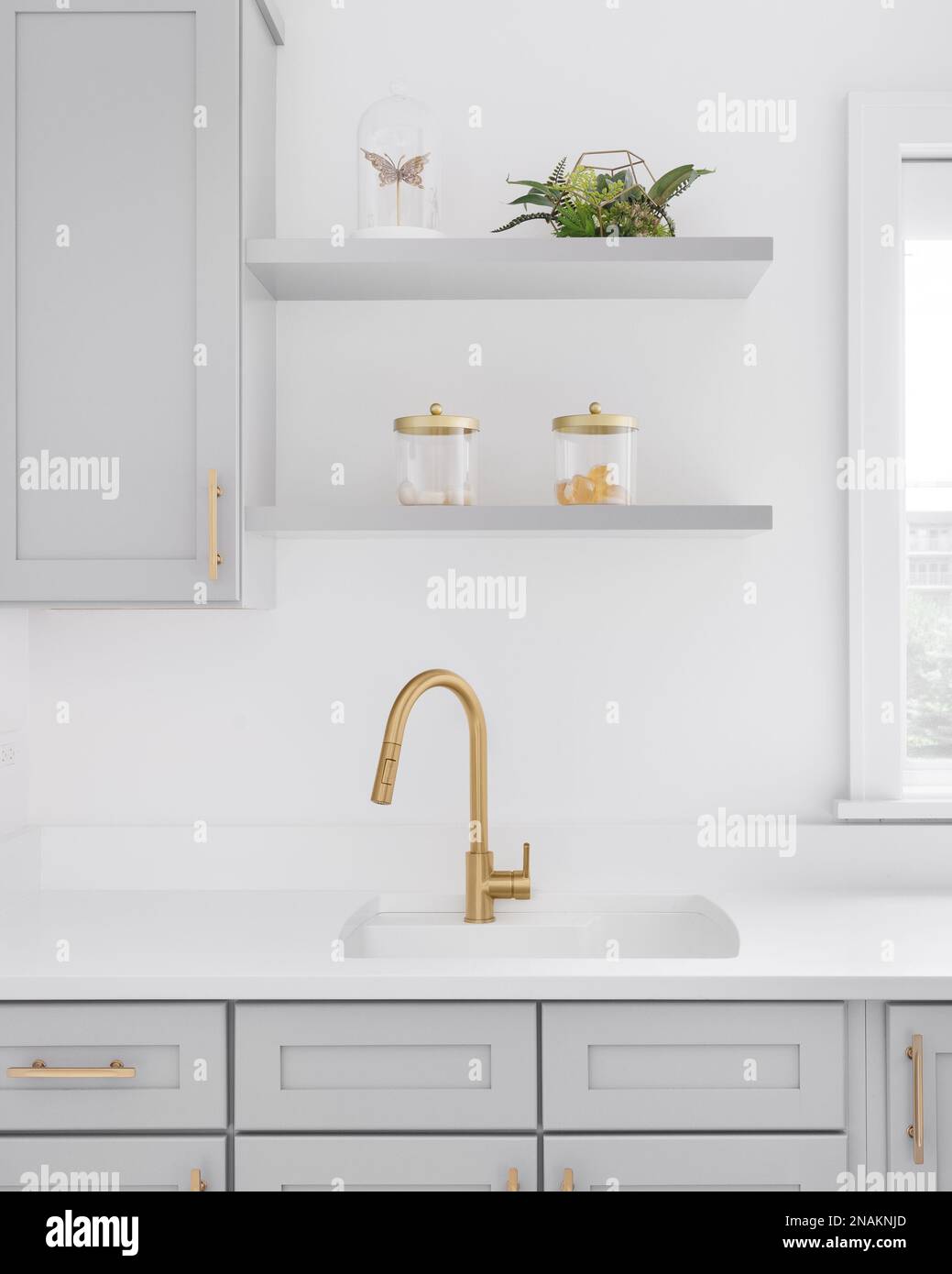 https://c8.alamy.com/comp/2NAKNJD/a-gold-faucet-detail-with-grey-cabinets-white-marble-countertop-and-decorations-on-shelves-2NAKNJD.jpg