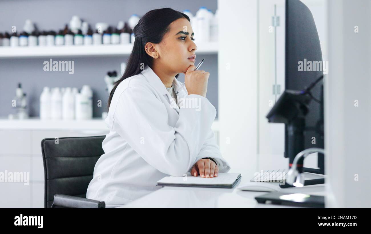Young scientist using a computer and microscope in a lab. Female pathologist analyzing medical samples while doing experiments to develop a cure Stock Photo