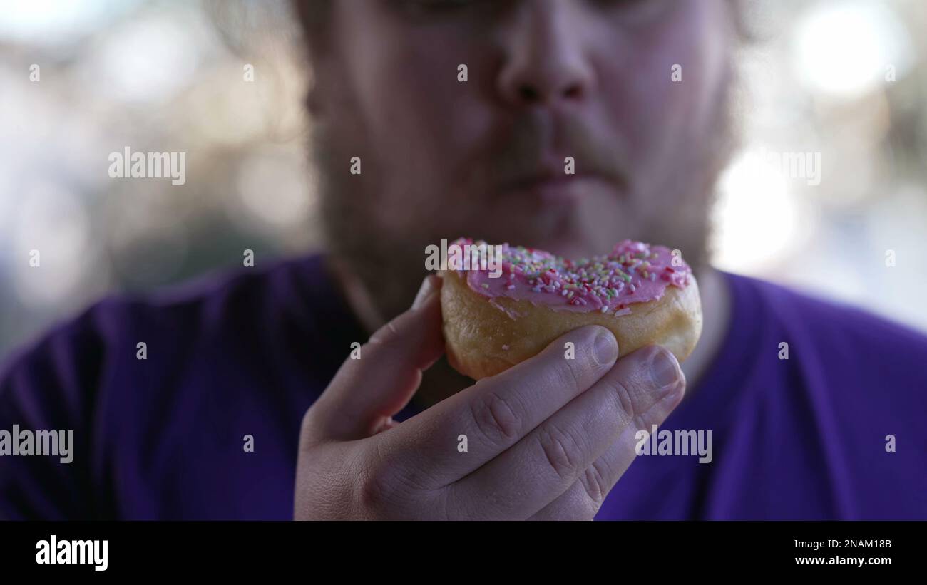 One fat man eating donut snack. Overweight person eats junk food. Guy