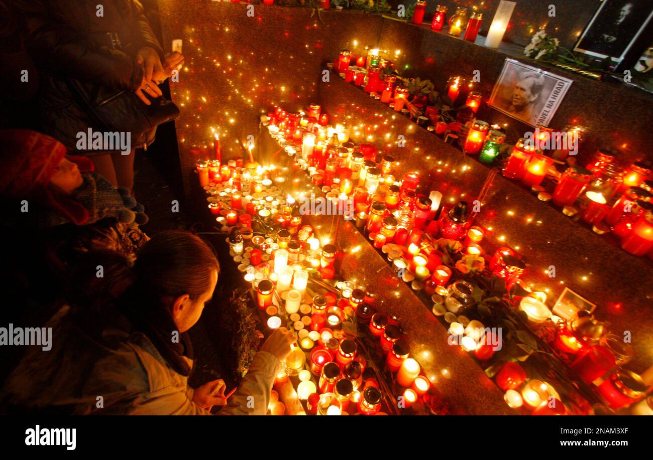 People gather to lay flowers and light a candle to commemorate the death of former Czech