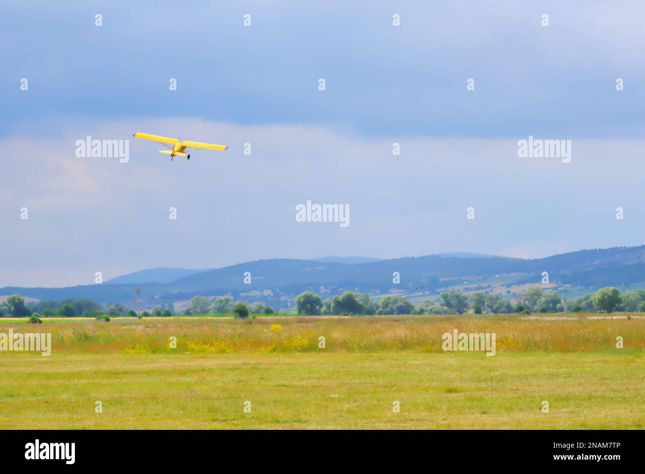 Yellow single engine airplane taking off from the field Stock Photo