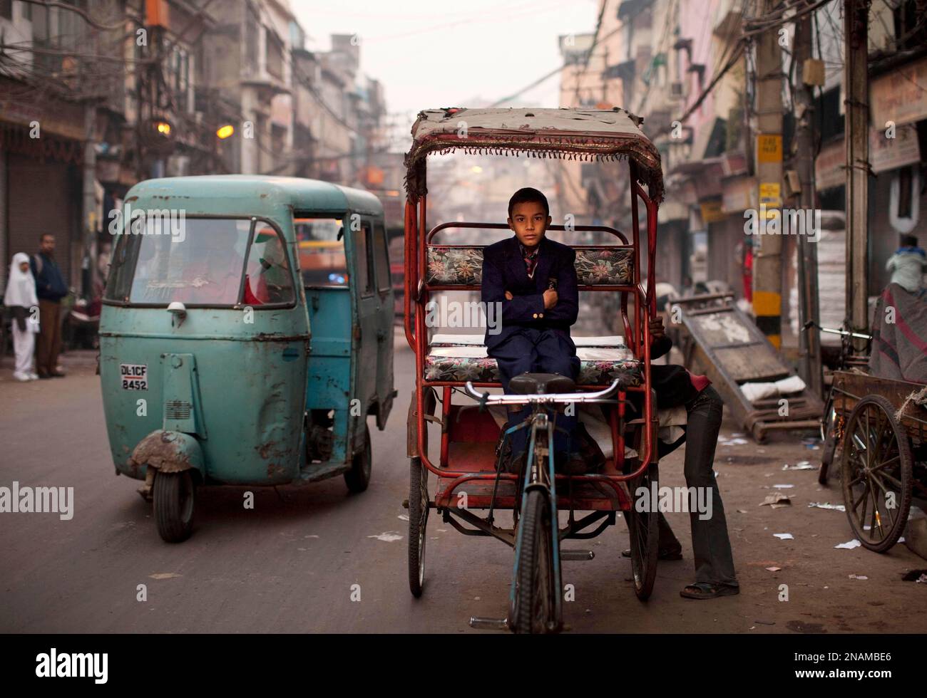 An Indian boy in school uniform waits for a rickshaw driver to make an ...