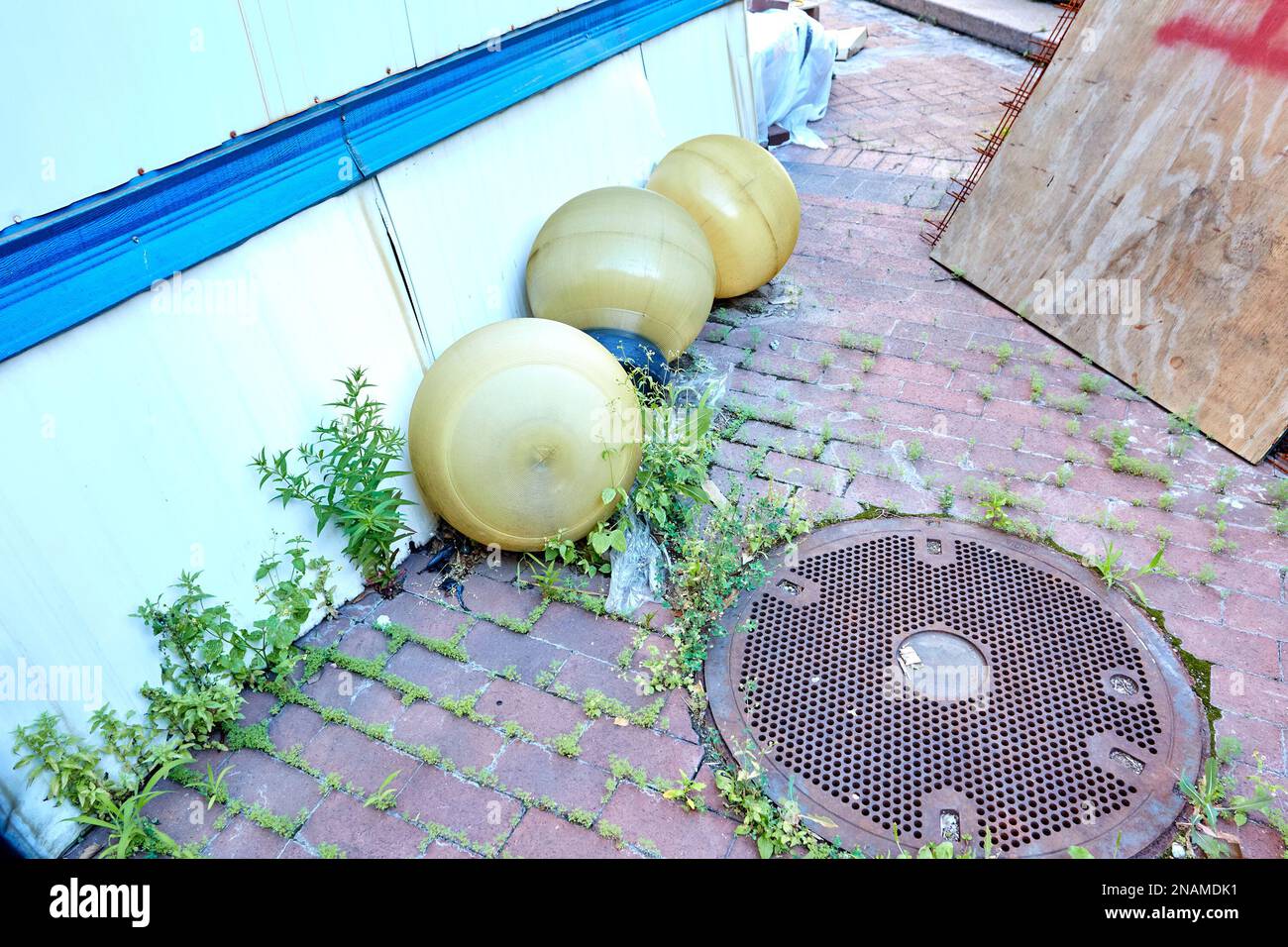 Streetlight Globes on Brick Sidewalk with Manhole Cover and Weeds Stock Photo