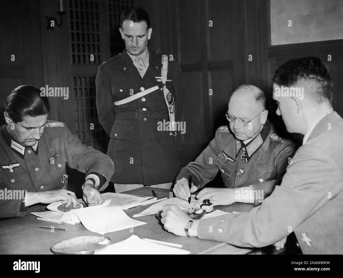Lieut. General Erich Brandenberger signing the unconditional surrender  terms in Innsbruck, Germany on May 10, 1945. On his right is Councilor  Lohrmann of the German War Office and on his left Major