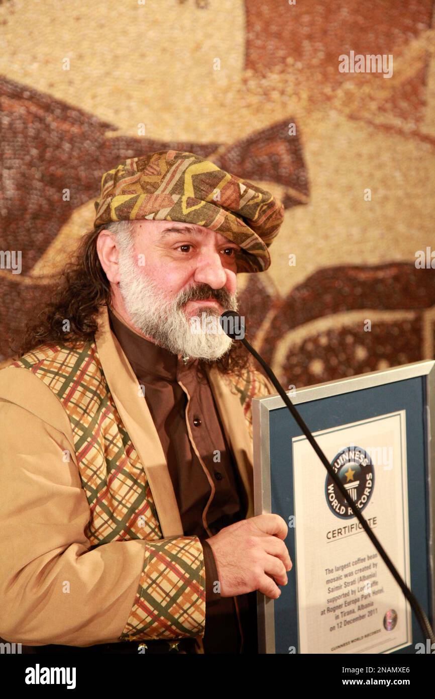 Albanian artist Saimir Strati 45 poses in front of his coffee bean mosaic with his Guinness World Records certificate in Tirana December 12 2011. The mosaic made with a million coffee beans