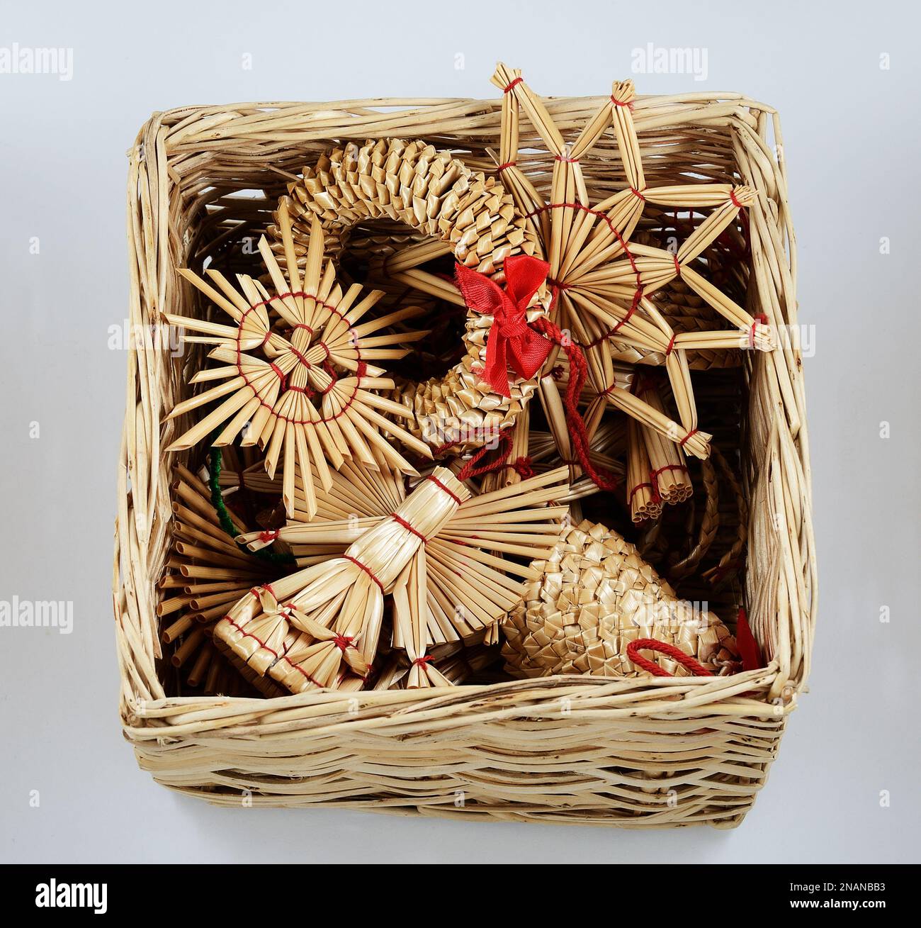 traditional Christmas straw decorations in a wicker box on a neutral background Stock Photo