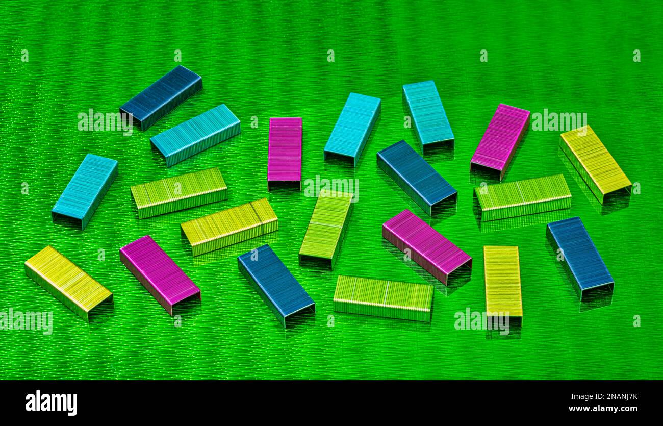 multi colored metal staples on green abstract background Stock Photo