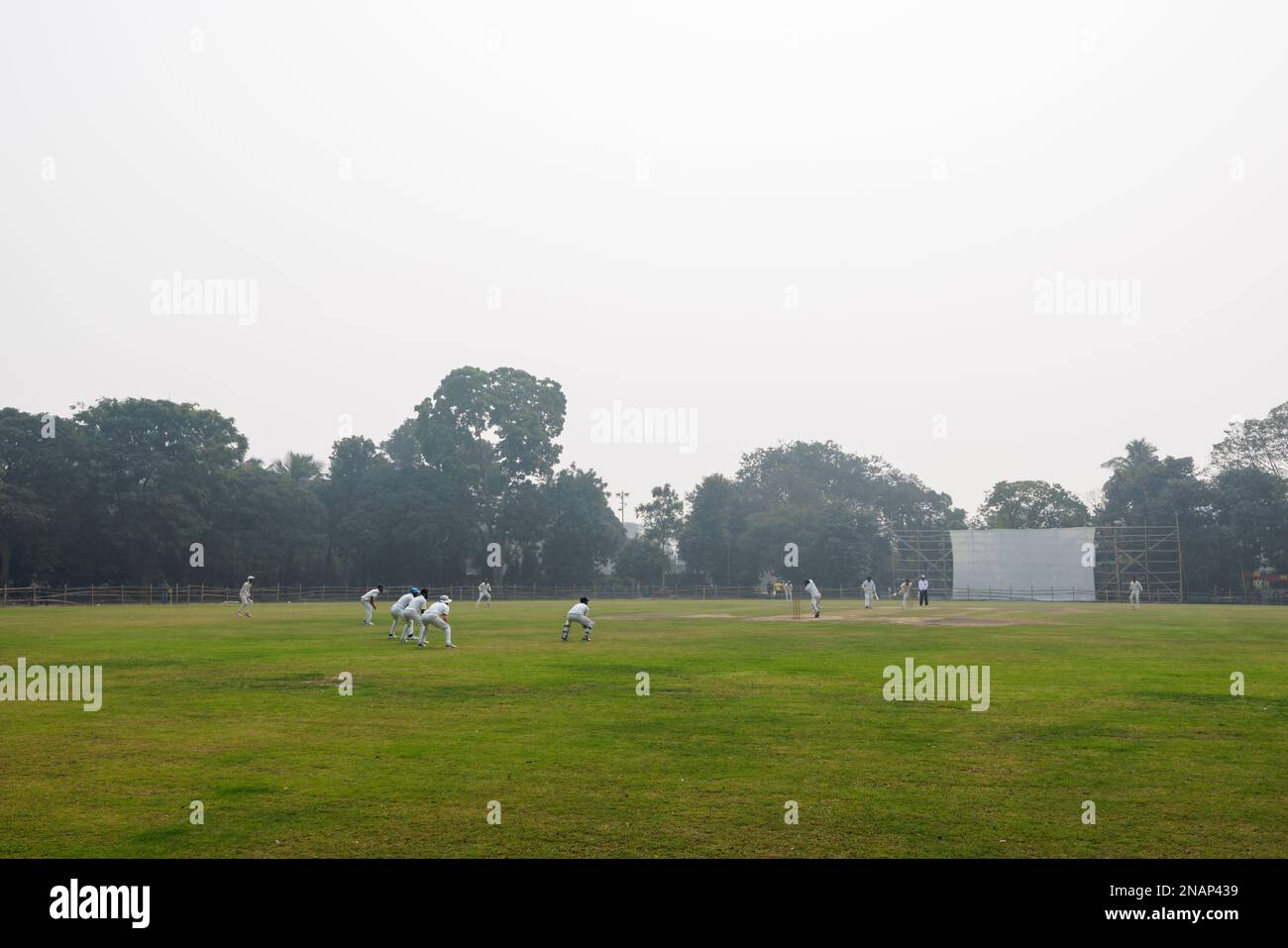 Cricket being played in Deshbandhu Park in Fariapukur, Shyam Bazar, a suburb of Kolkata, West Bengal, India on a smoggy day Stock Photo