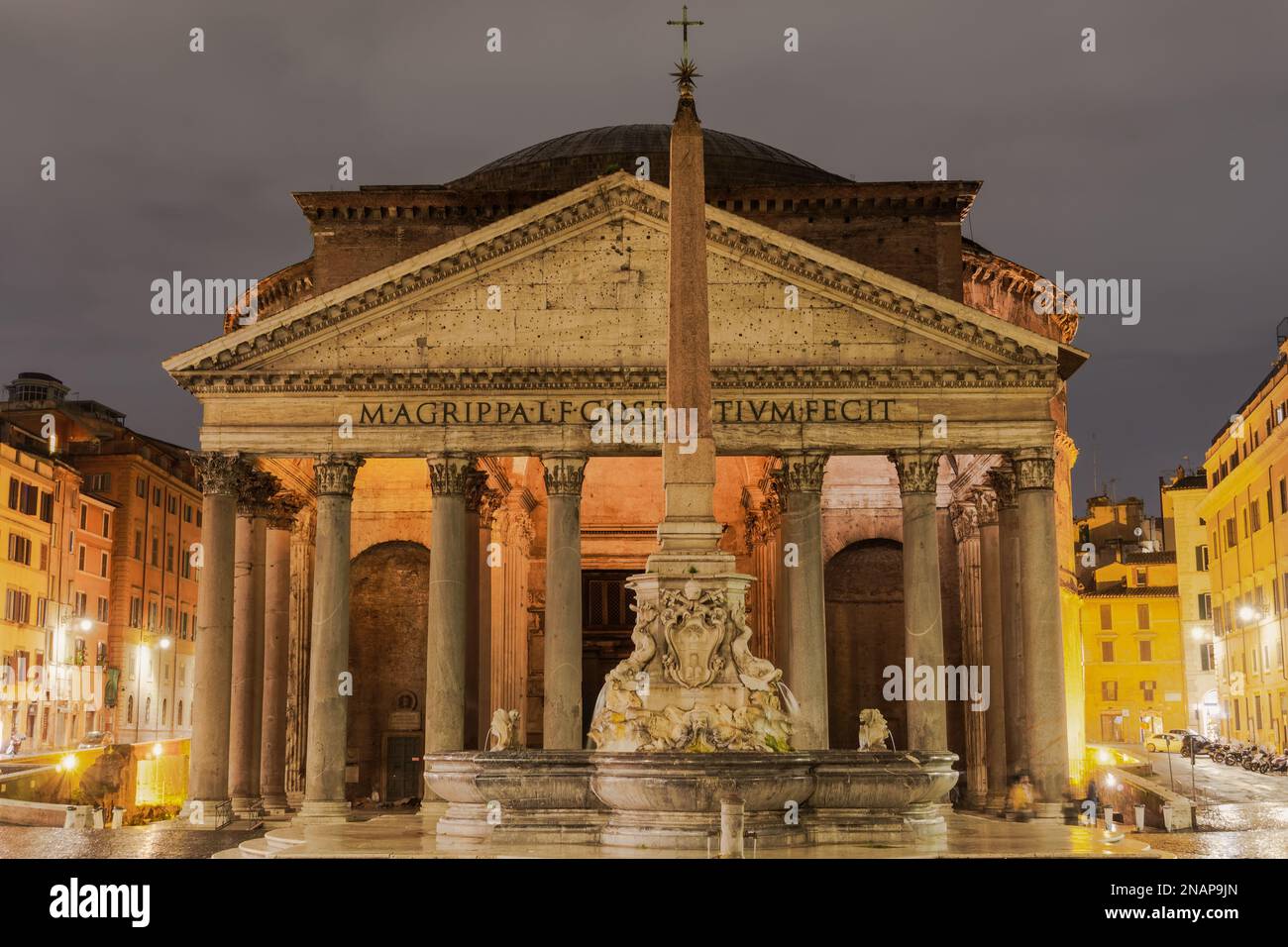 Rome, Italy cylindrical Pantheon monument facade at night. Iconic dome temple at Rotonda square with fountain, obelisk & surrounding buildings visible. Stock Photo