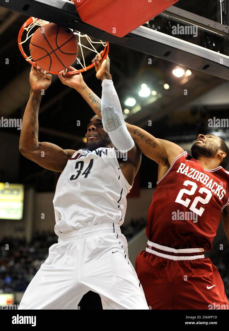 Connecticut's Alex Oriakhi, left, dunks the ball while guarded by Arkansas' Marvell Waithe (22