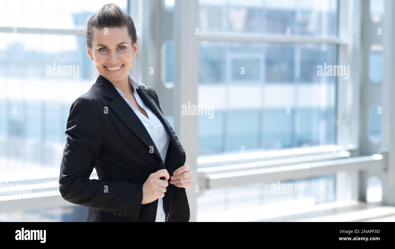 Smiling Pretty Business Woman standing in office lobby looking at ...