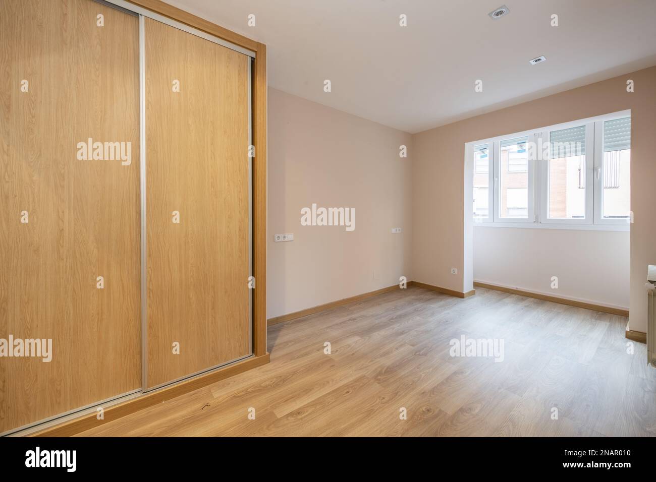 An empty room with a pomegranate terrace for the living space with a white aluminum window and a built-in wardrobe with sliding oak doors Stock Photo