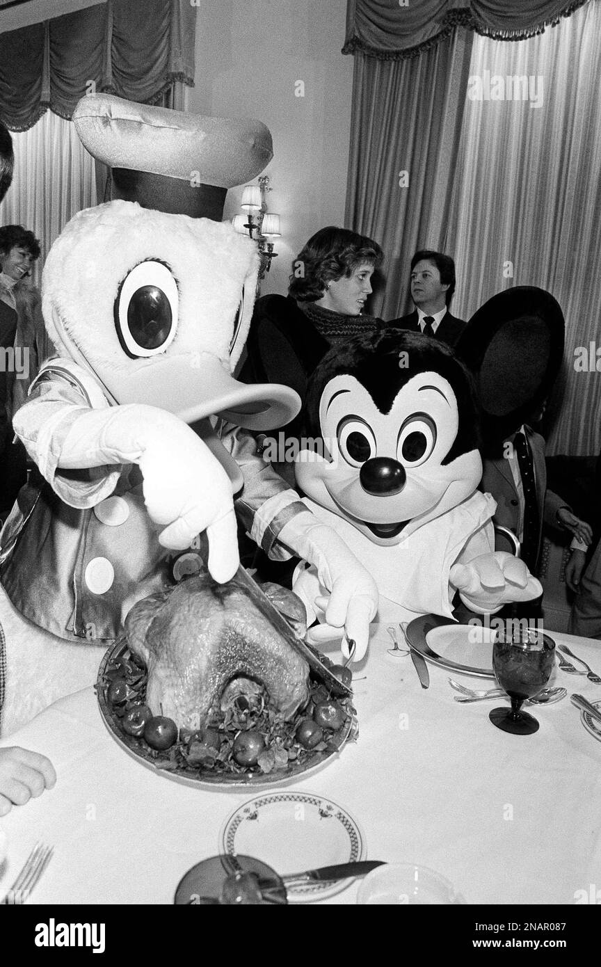 Donald Duck carves the traditional turkey while Mickey Mouse looks on ...