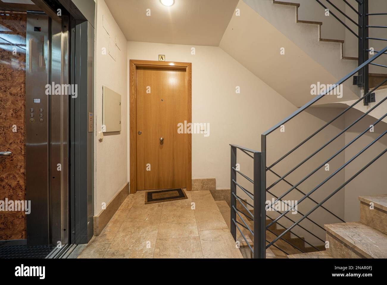 Interior of a residential apartment portal with an elevator with gray metal doors and polished cream marble floors, gray metal railings and marble sta Stock Photo