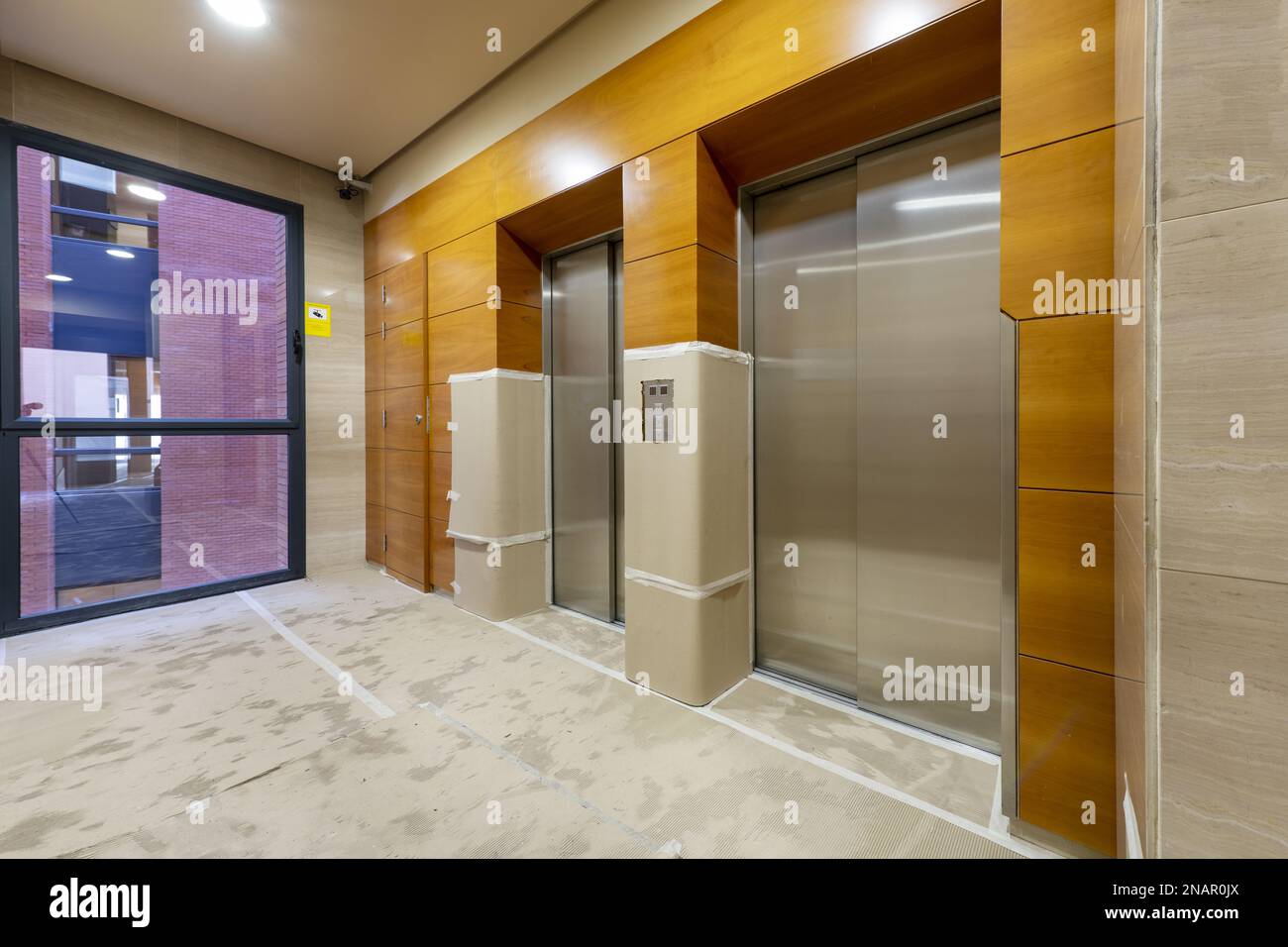 Elevator area of an office building with walls and floors covered with cardboard due to being under construction Stock Photo