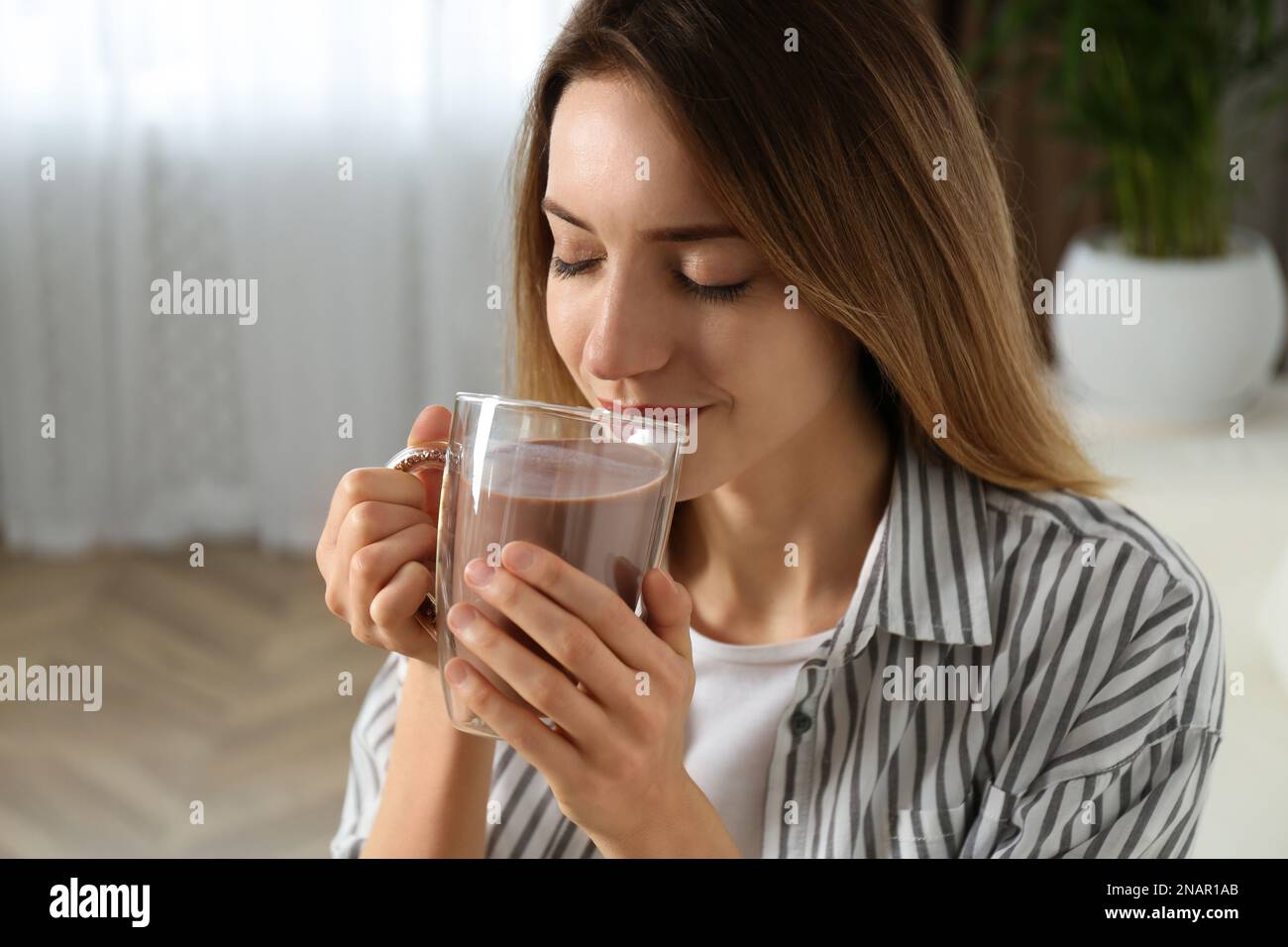 Young woman drinking chocolate milk in room Stock Photo Alamy