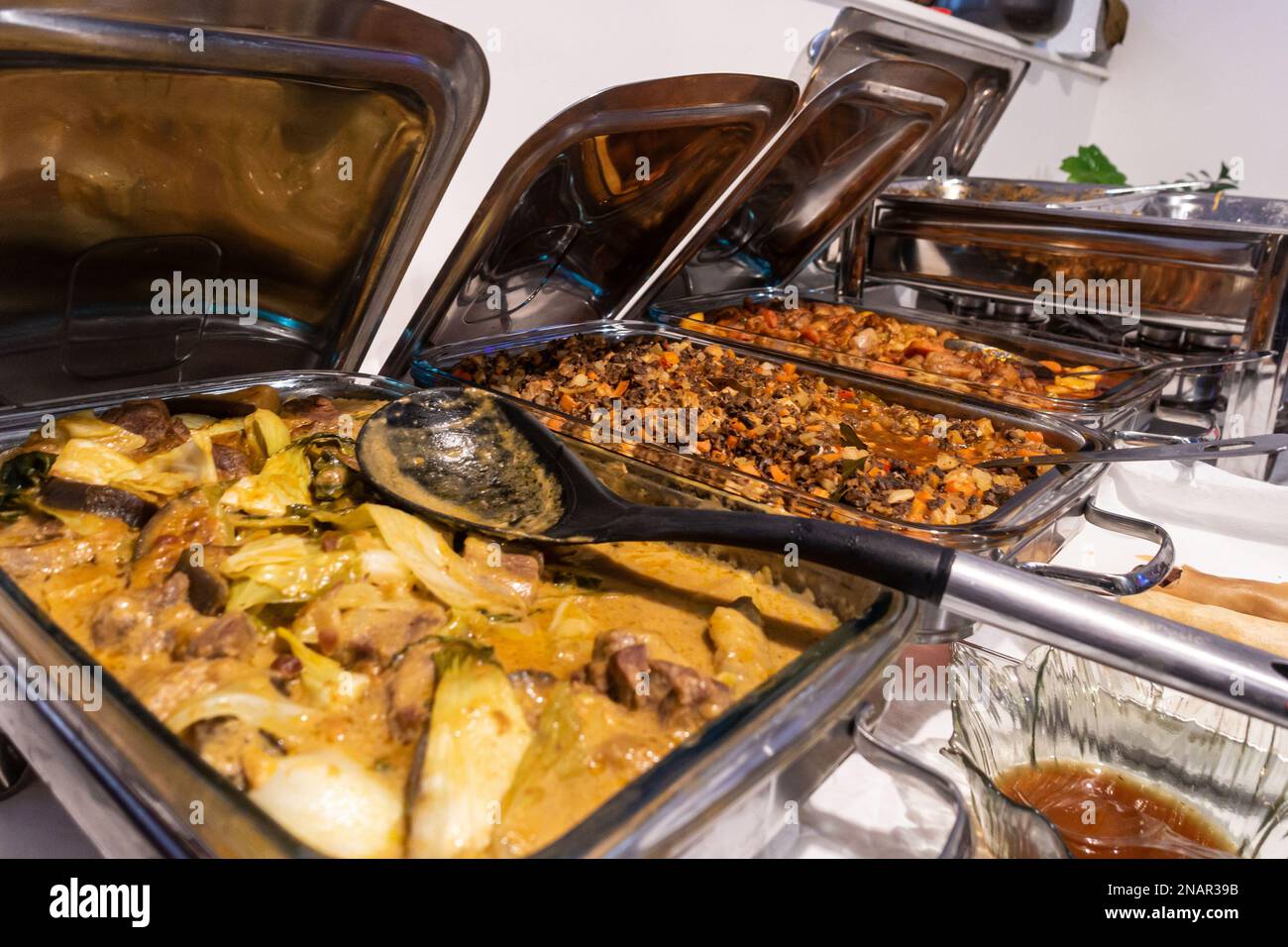 A buffet selection of filipino dishes in stainless steal chafing dishes at a party Stock Photo