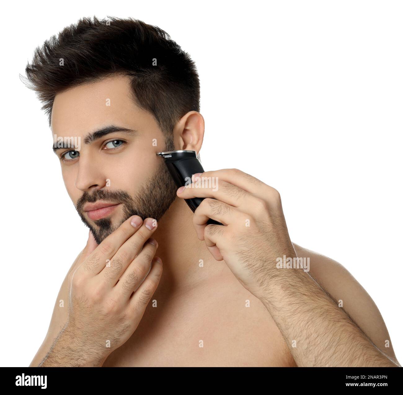 Handsome young man shaving with electric trimmer on white background