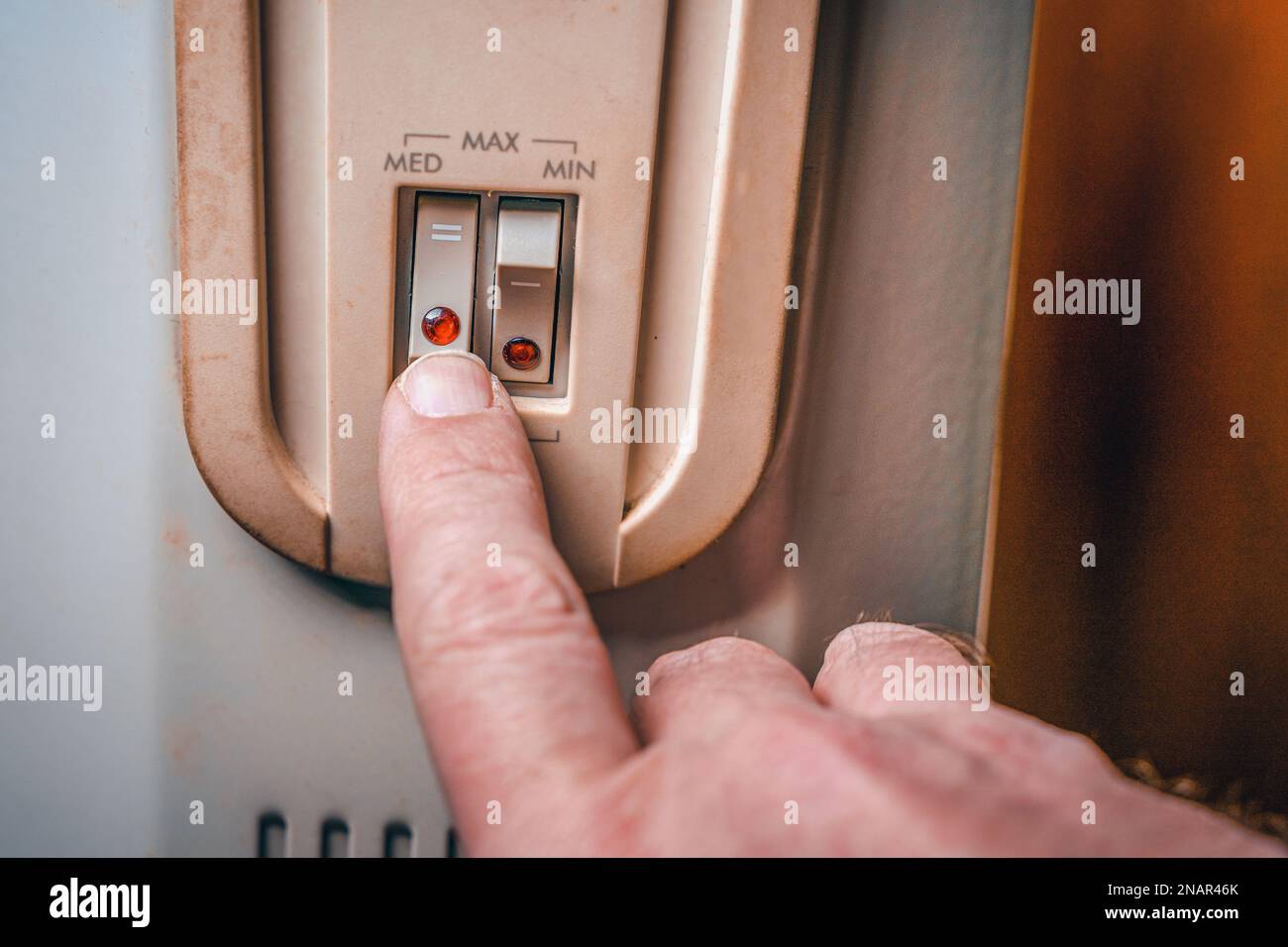 The man turns on the heater. Close-up of the hand, power buttons and ...