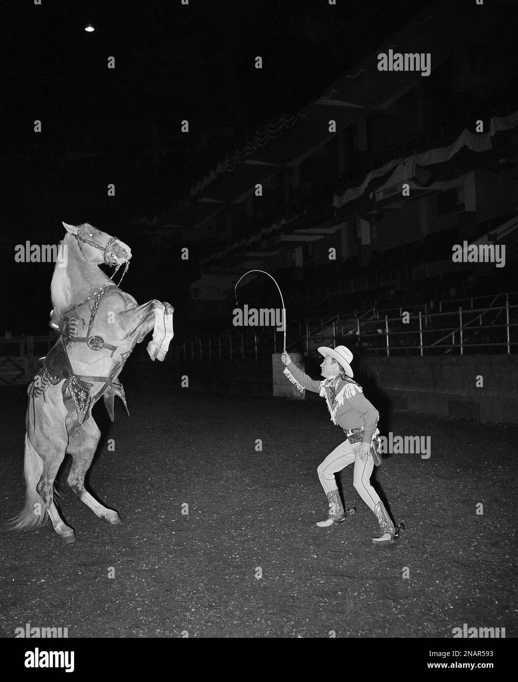 Roy Rogers, featured performer of the rodeo, performs a stunt with his ...