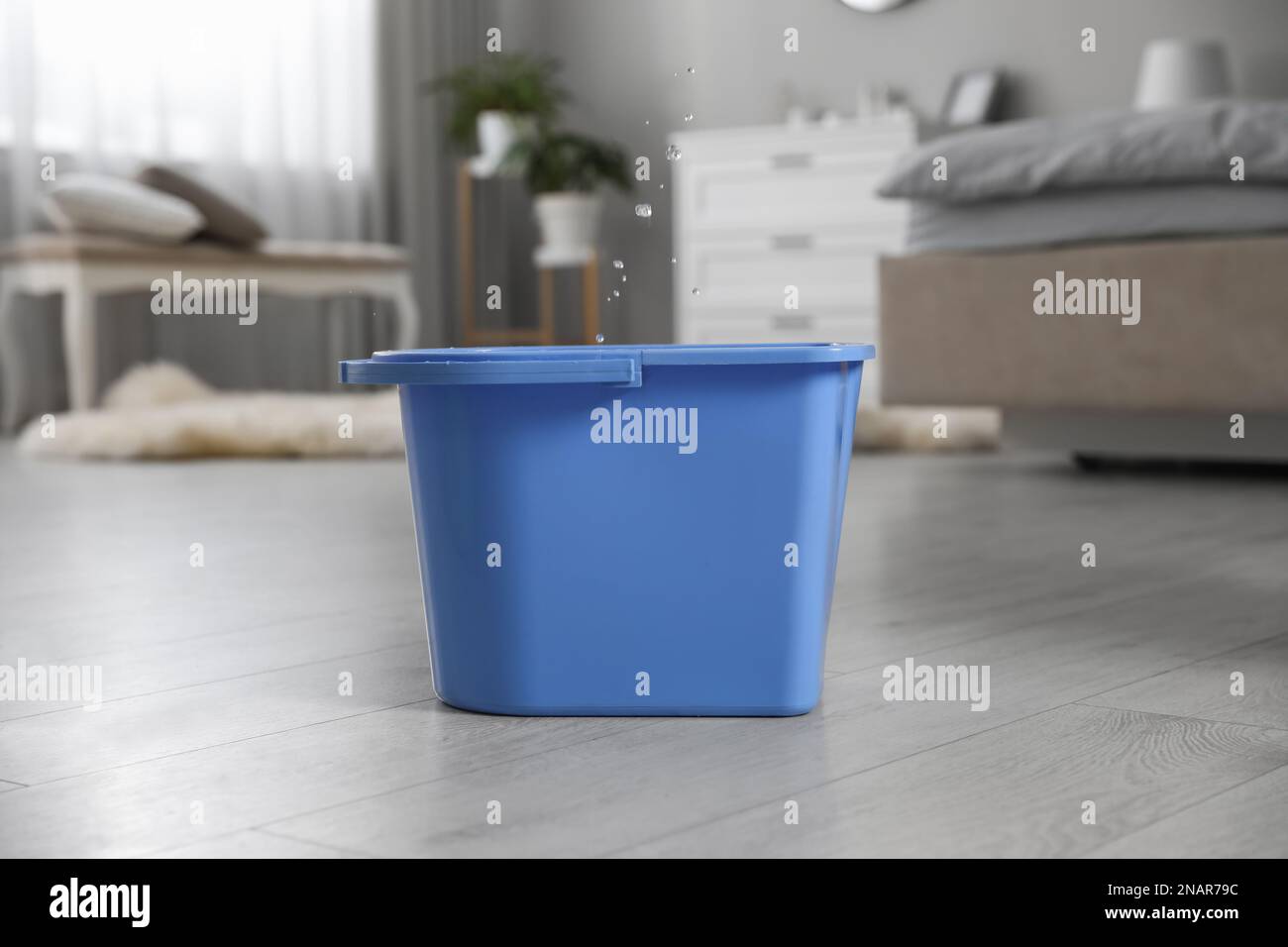 Bucket collecting leaking water from ceiling indoors. Time to call roof