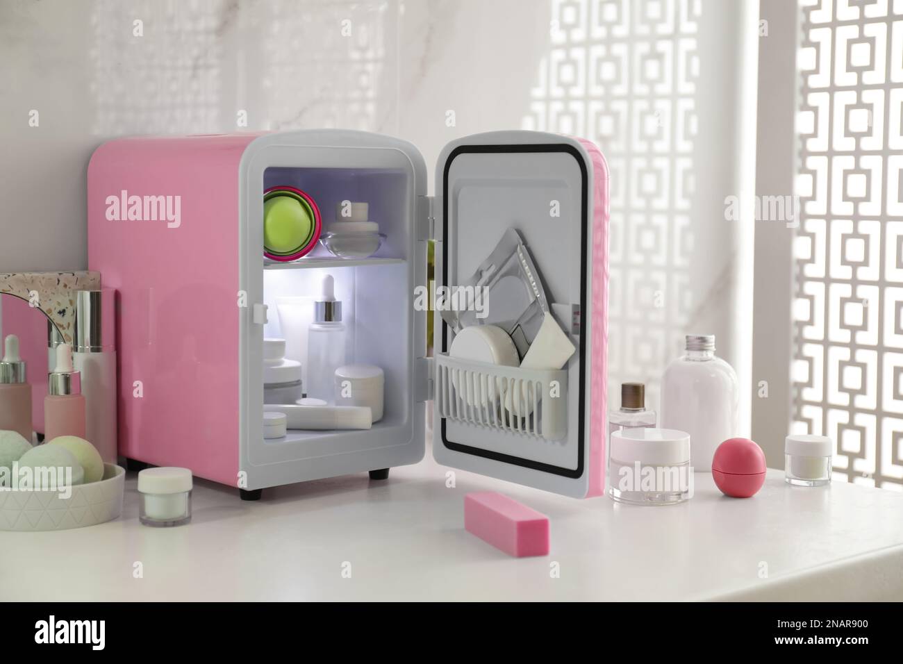 Cosmetics refrigerator and skin care products on white table indoors