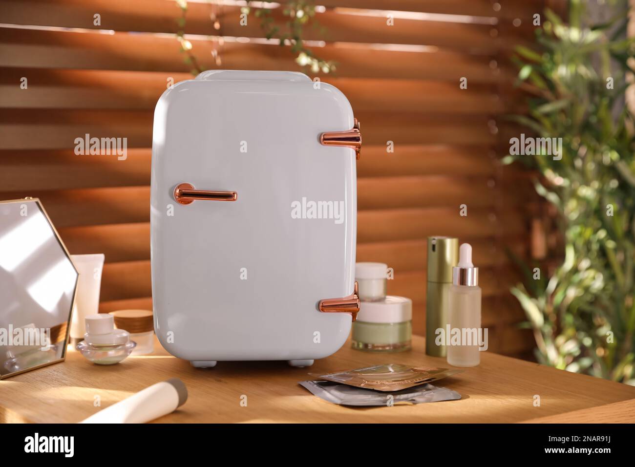 Mini fridge for cosmetic products on wooden vanity table Stock Photo