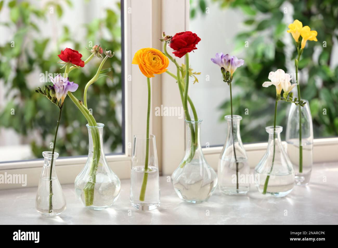 Different beautiful spring flowers in glassware on window sill Stock ...