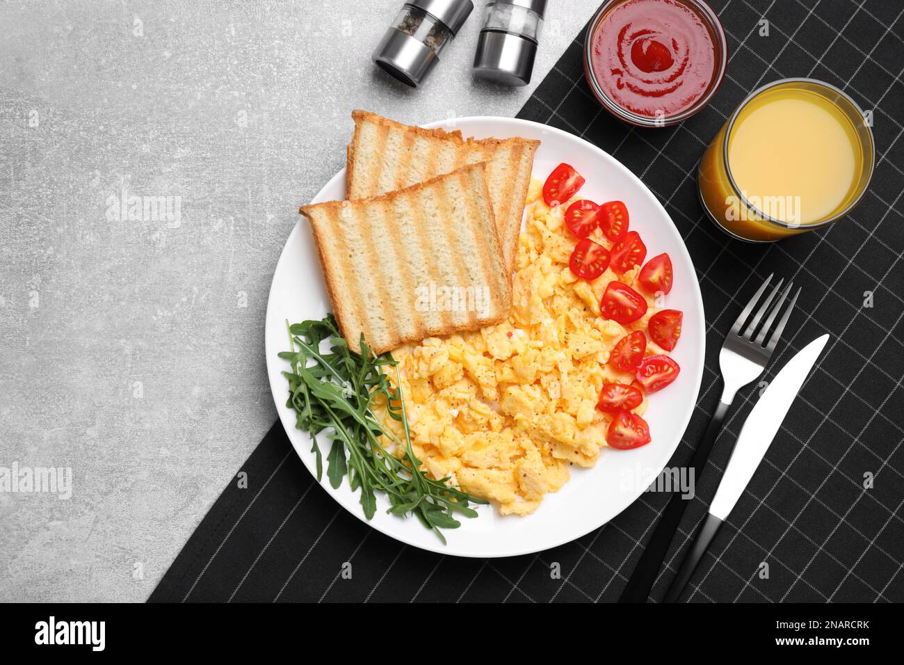 Delicious scrambled eggs served on light grey table, flat lay Stock Photo