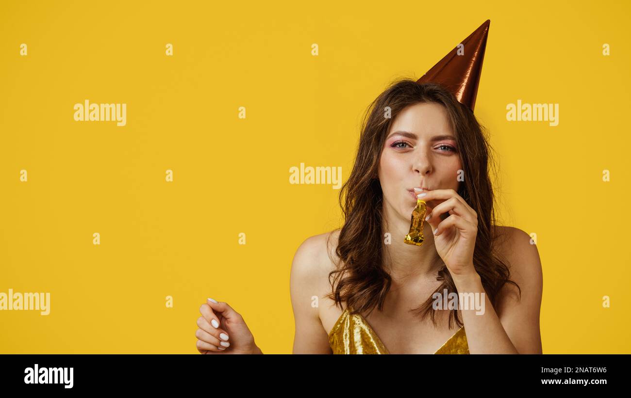 Pretty caucasian woman in birthday cap blowing party horn, celebrating ...