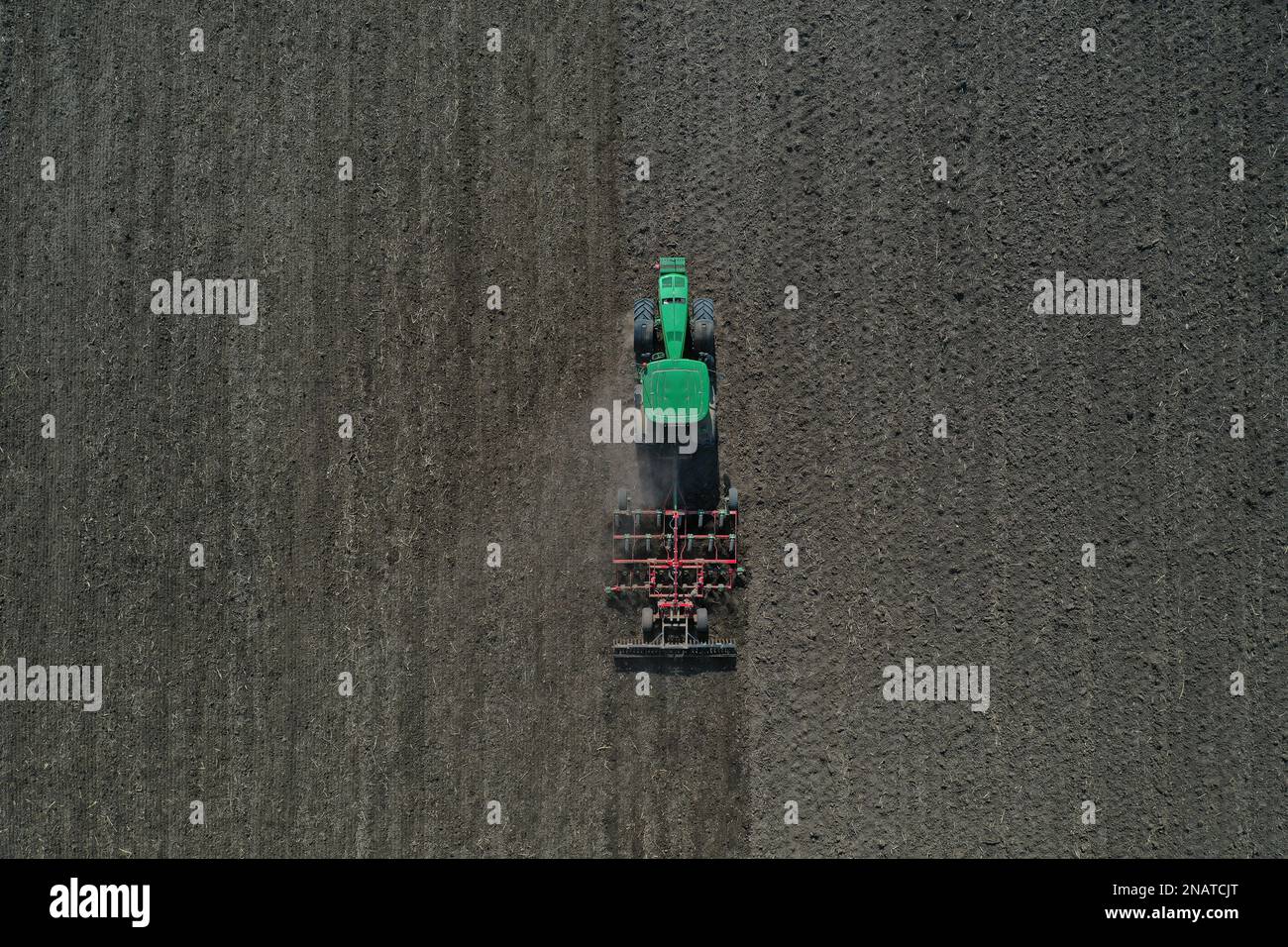 The farmer works with the tractor during the early spring season. Aerial view of mounted tractor while working. Stock Photo