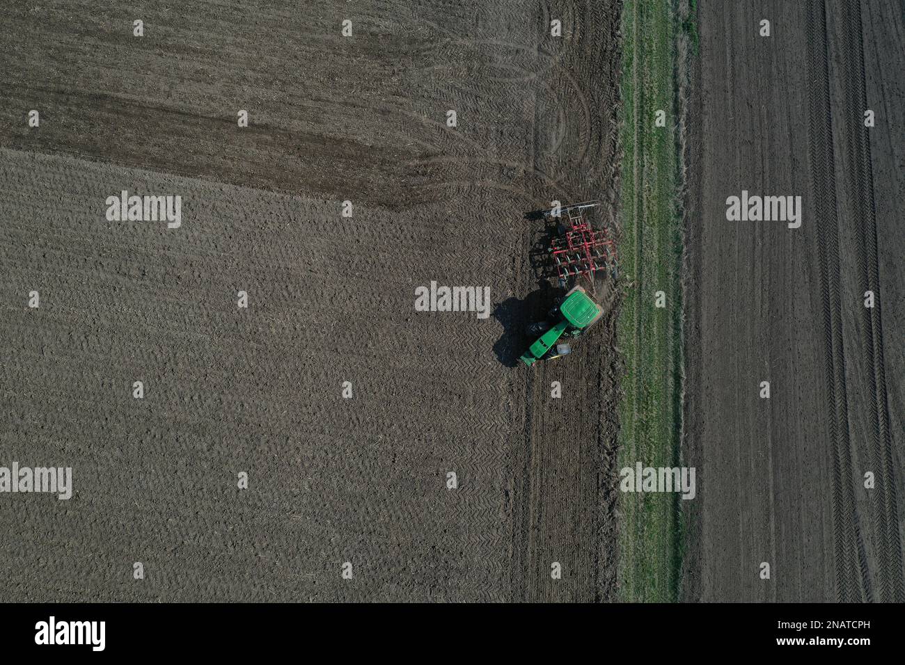 The farmer works with the tractor during the early spring season. Aerial view of mounted tractor while working. Stock Photo