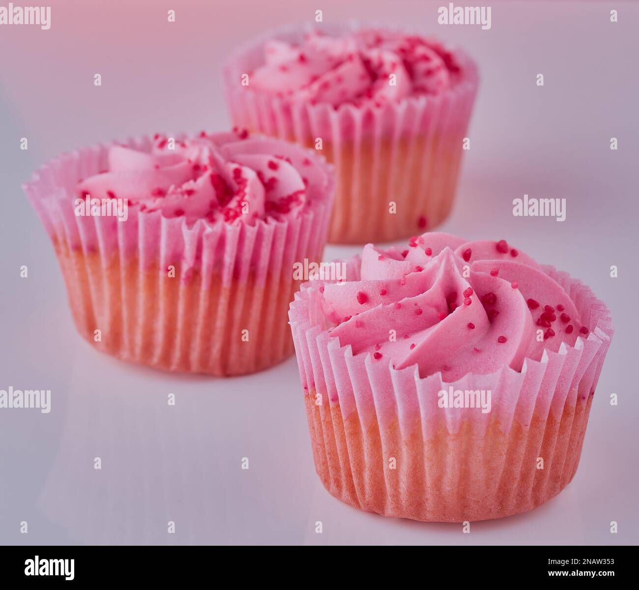 Three isolated cupcakes on plain background. Stock Photo