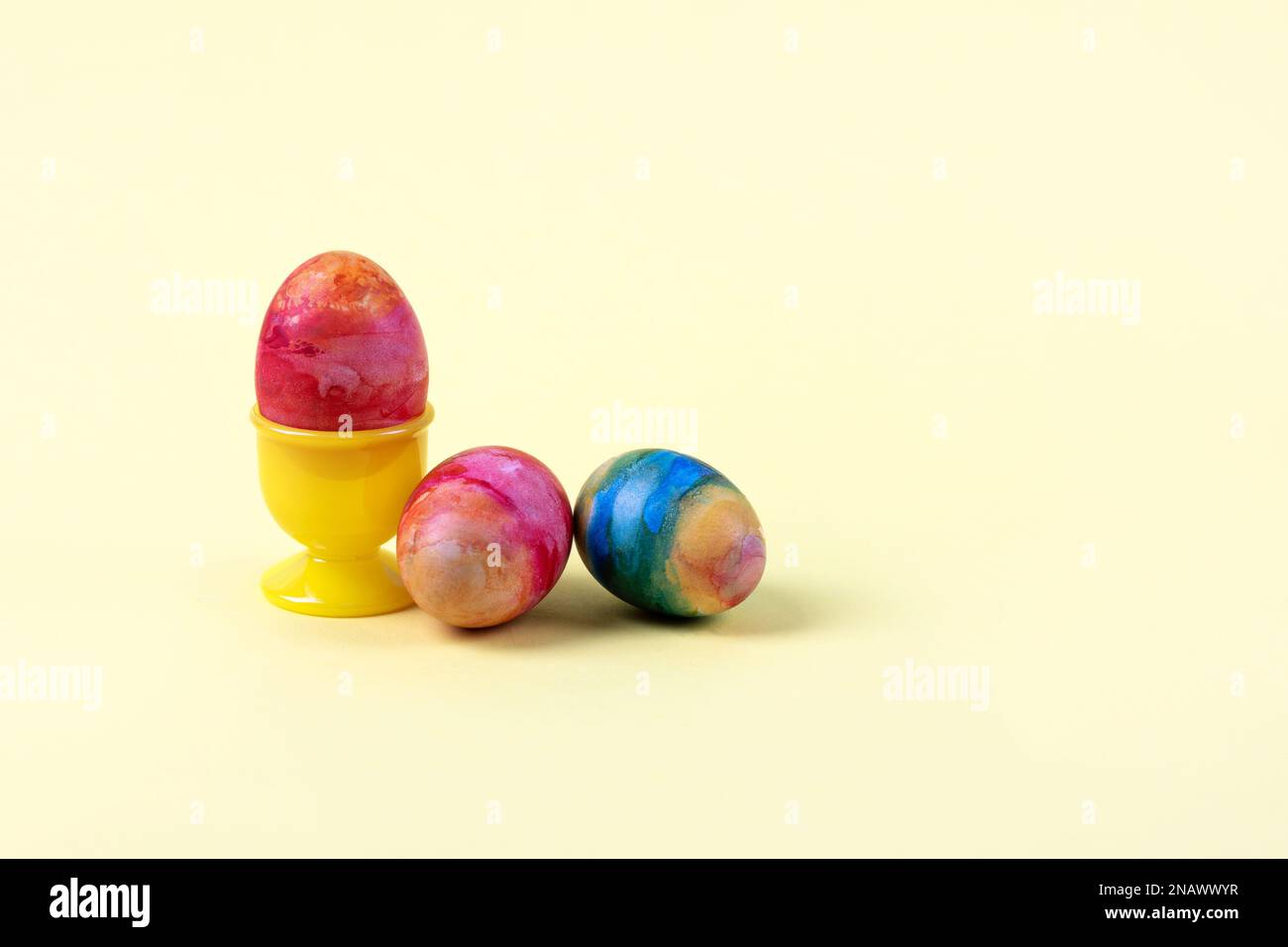 Three Easter multicolored eggs on a yellow background. Happy Easter concept. Greeting card. Stock Photo