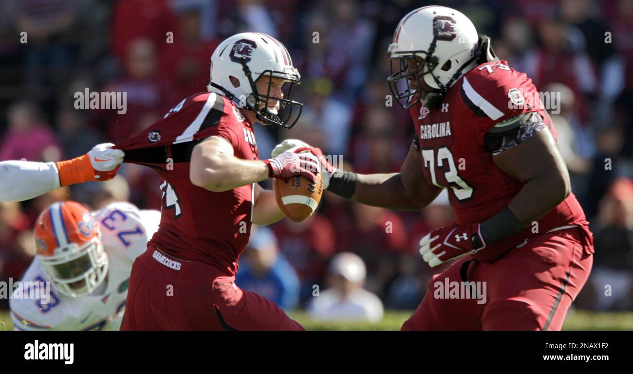 South Carolina quarterback Connor Shaw left is dragged down by his jersey by a Florida defender as offensive tackle Rokevious Watkins right looks on during the first half of a NCAA college