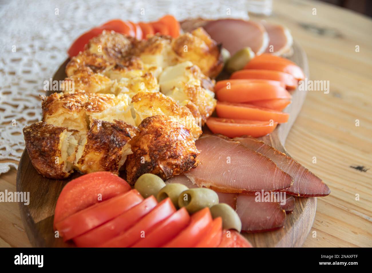 Serbian traditional food plate contain beef and pork smoked dried meet, cheese, vegetables and proja bread made of corn flour , served at wooden plate Stock Photo