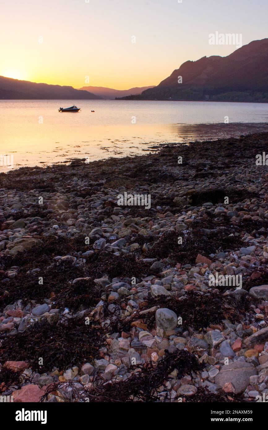Dusk over the calm waters of Loch Duich, Scotland, with its shingle beach in the foreground Stock Photo