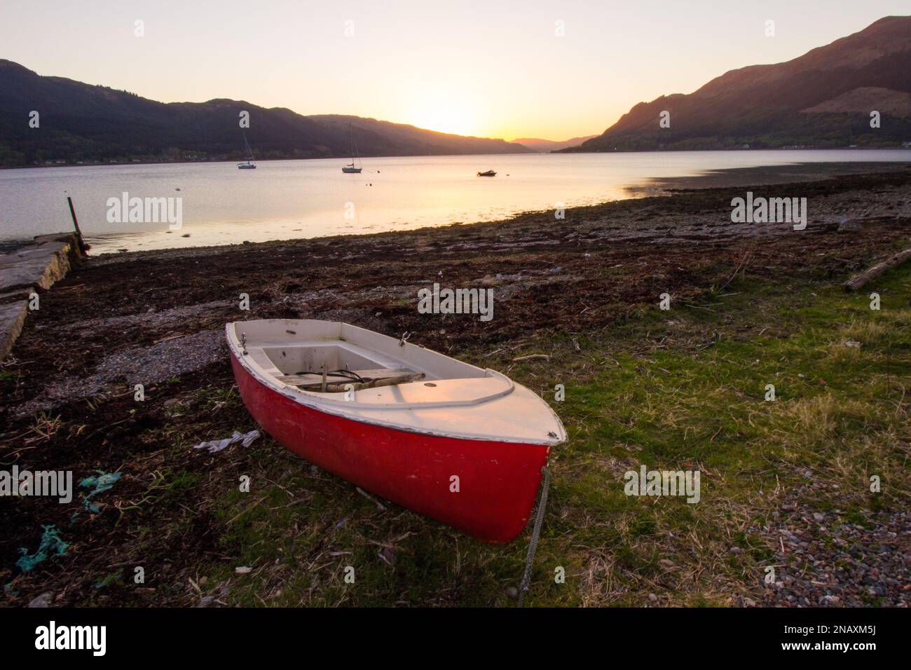 Sunset over Loch Duich, Scotland, with a single red beached rowboat Stock Photo