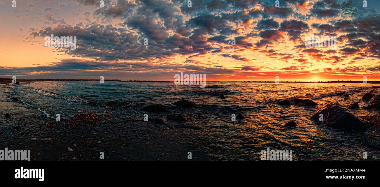 Golden sun dips below horizon, casting a warm glow over the ocean ...