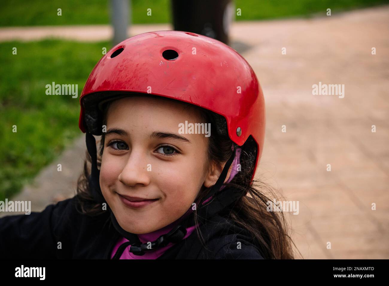 closeup of a little girl with the red helmet for her scooter in a skatepark. Stock Photo