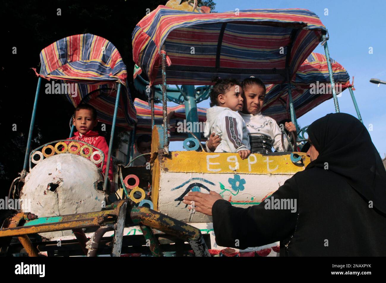 An Egyptian woman supervises her children on swings at a popular park