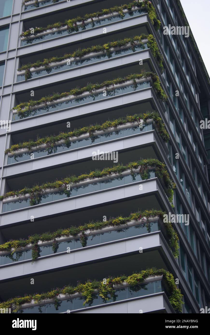 Green building facade with planters on glass gardrail balconies in ...