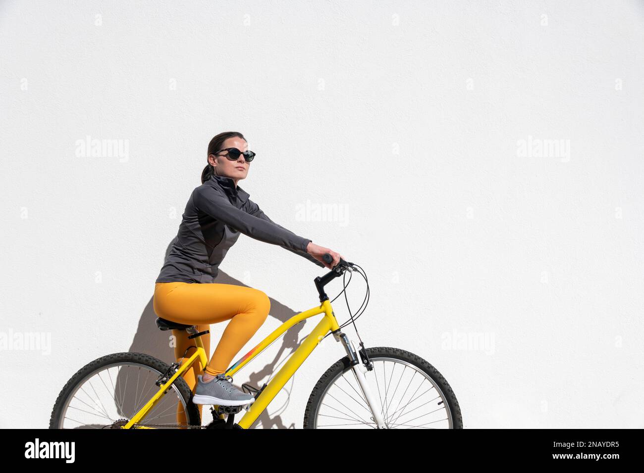 Fit, female cyclist riding a yellow bicycle Stock Photo